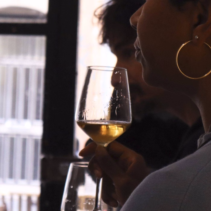 a glass of white wine from Jerez is held up against a stark backlight
