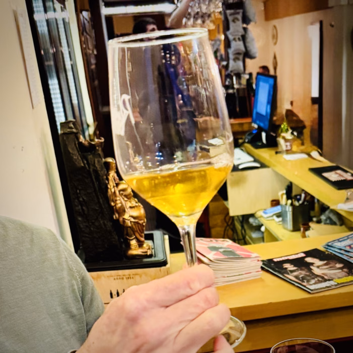 a glass of beer is help up in a wine glass on a barcelona craft beer tour