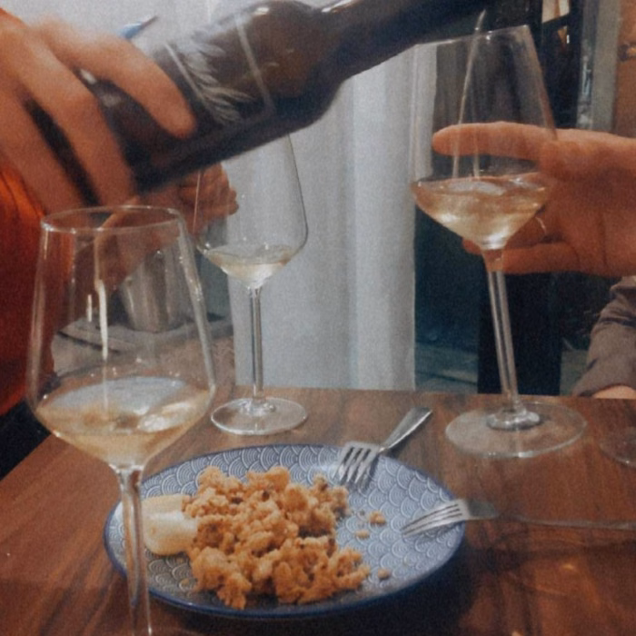 a glass of wine is poured in front of a plate of calamari