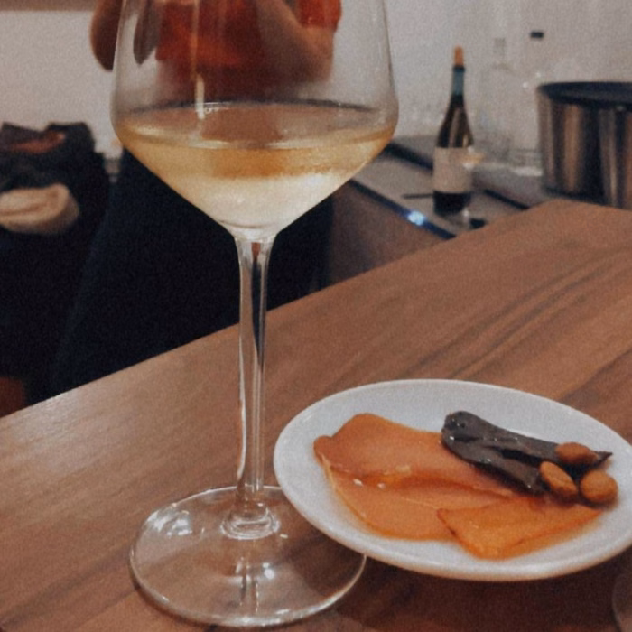 a glass of white wine and a plate of smoked fish